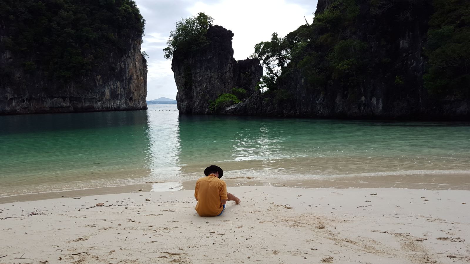 A quiet beach with turquoise water beneath limestone cliffs in the Andaman Sea