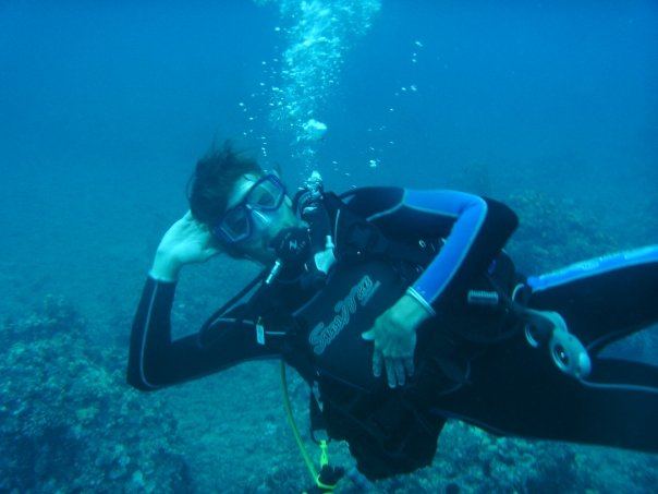 A diver in a wetsuit pausing above a reef in clear blue water