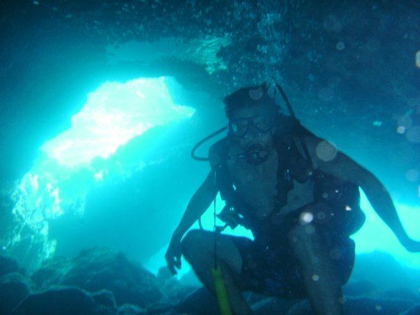 A diver silhouetted in a glowing blue underwater cave